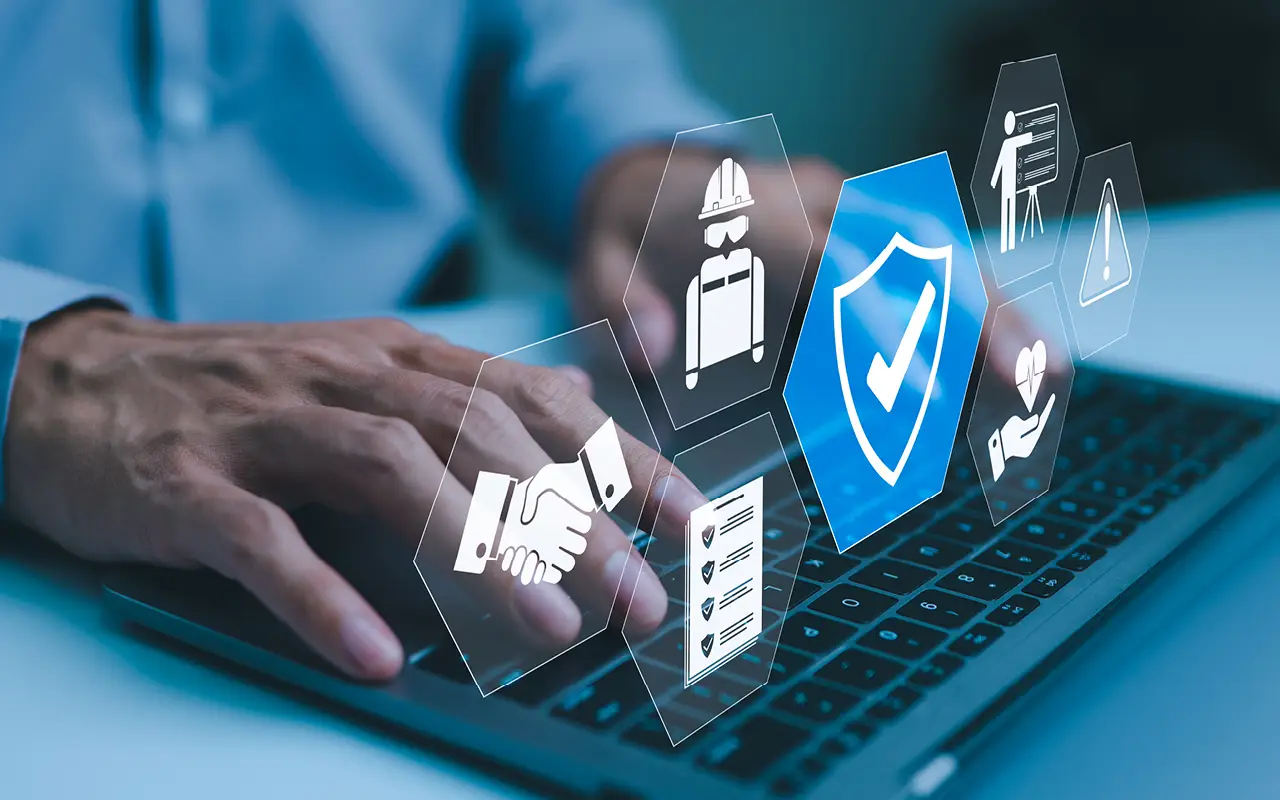 A close-up of a professional’s hands typing on a laptop, with futuristic digital compliance icons hovering above. The icons include a secure checkmark, a checklist, a handshake, a construction worker, a training symbol, and a warning sign, representing automated compliance workflows and regulatory adherence in insurance and workers’ compensation. The image conveys a modern, technology-driven approach to ensuring compliance and avoiding fines.